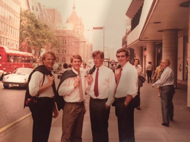 Four young white men in ties and button-up shirts standing in the middle of a downtown street